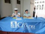 Caitlyn Lees, 2012 grad, sits at he sign in table with a cadet on Matriculation Day.